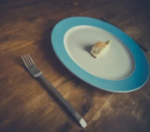 "Plato con un pequeño trozo de pan simbolizando la restricción alimentaria en la bulimia