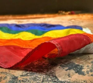 Bandera LGTBI caída sobre el suelo como símbolo de la violencia hacia la orientación sexual