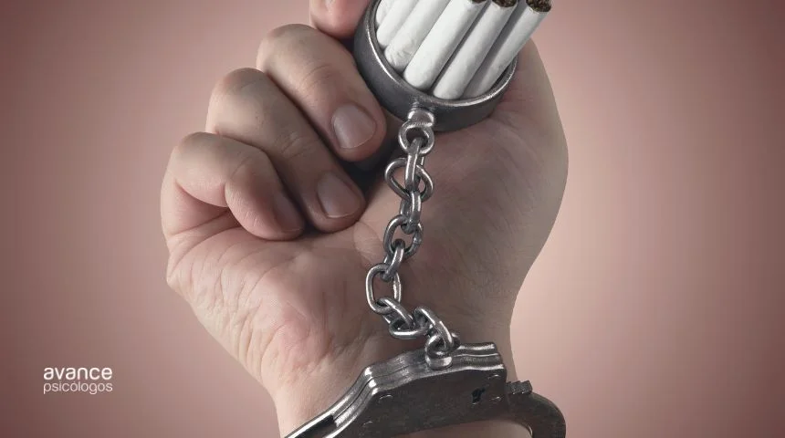Muñeca esposada a una cajetilla de cigarrillos, como metáfora visual de la adicción al tabaco.