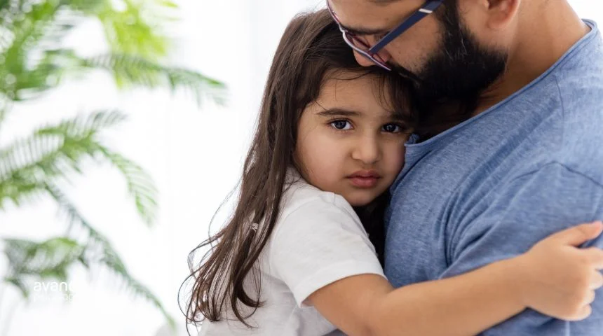 Niña abrazando a su padre con expresión seria, reflejo de ansiedad por separación infantil