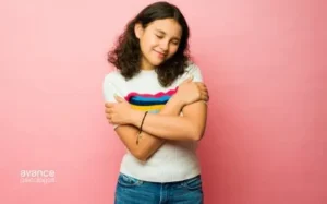 Mujer joven abrazándose a sí misma con expresión de bienestar, símbolo de autoestima alta