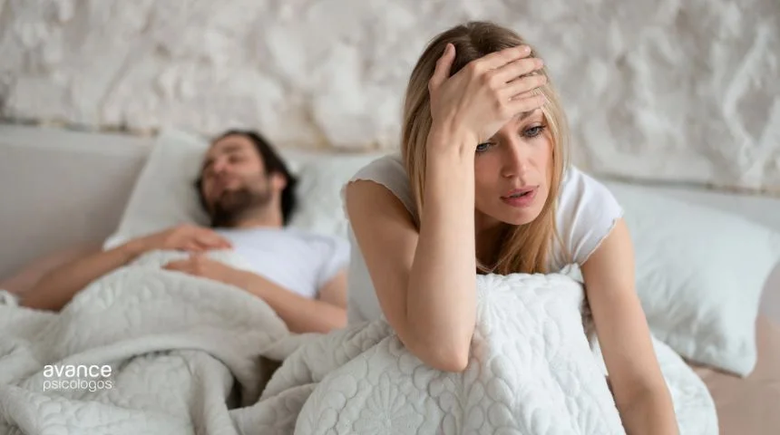 Mujer con falta de libido sentada en la cama, preocupada por el deseo en la pareja