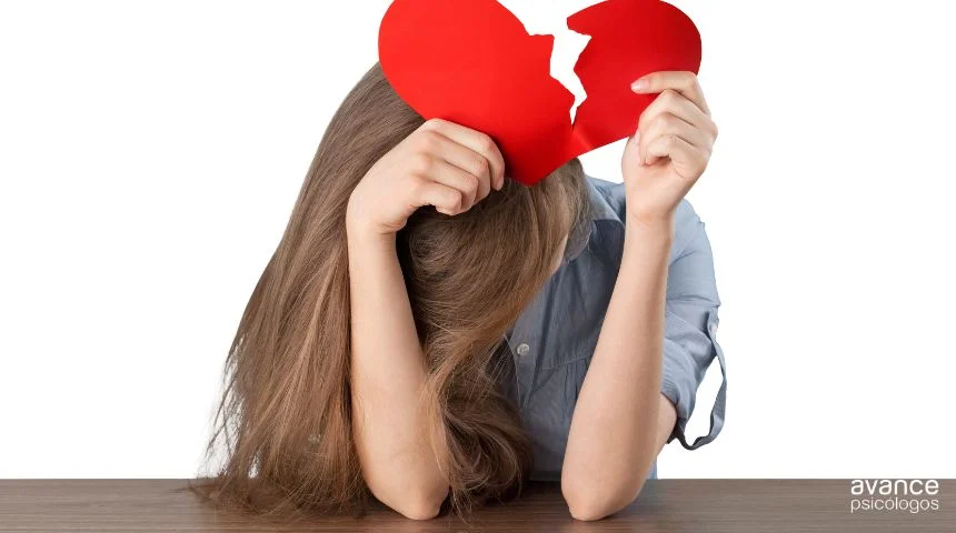 Mujer con la cabeza gacha sosteniendo un corazón roto tras una ruptura sentimental