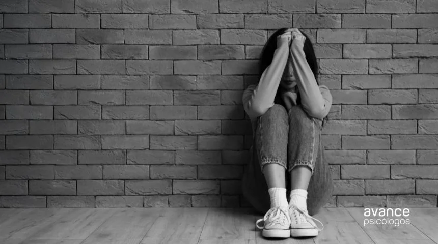 Pensamientos intrusivos involuntarios: mujer sentada con angustia junto a pared de ladrillo