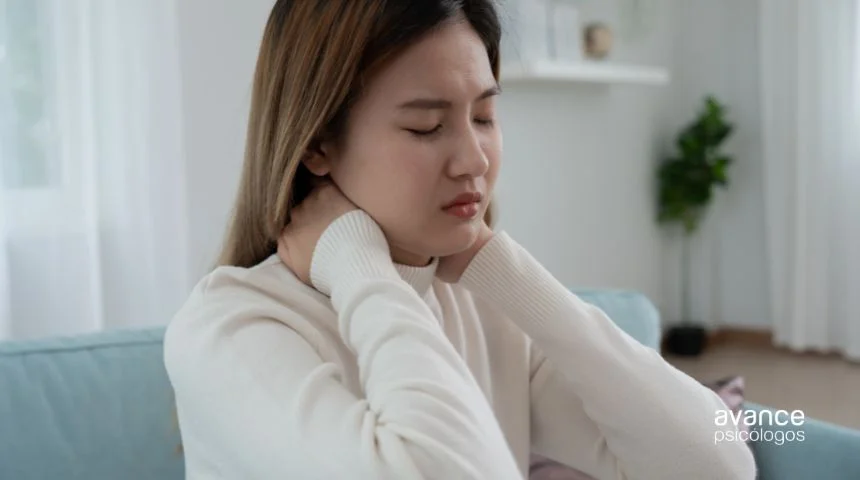 Síntomas del estrés crónico: mujer con tensión cervical y gesto de dolor